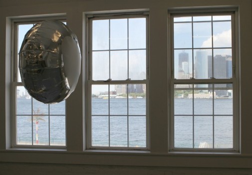 A wistful balloon awaits the truth by the gallery window, with the skyline of Lower Manhattan in the distance.